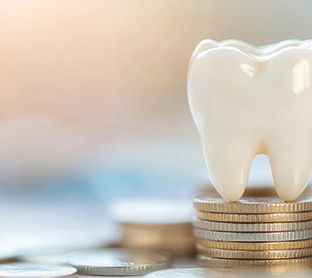 Tooth model sitting on top of stack of coins