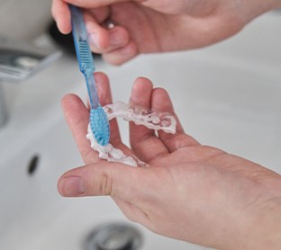 Patient using toothbrush to clean aligners