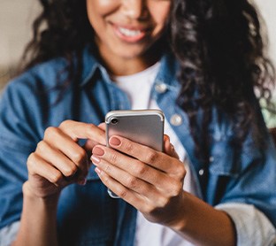 Woman smiling while looking at phone on couch