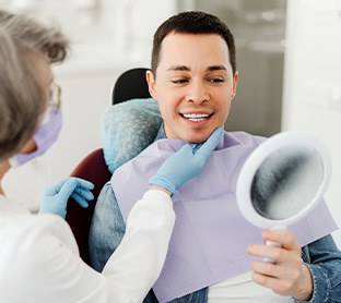 Man smiling at reflection in mirror with dentist