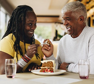 Couple smiling while enjoying slice of cake together