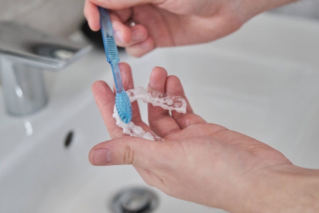 Patient using toothbrush to clean aligner